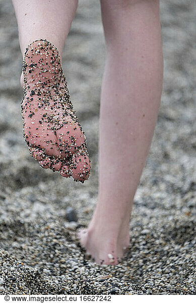 Woman foot covered with gravel while standing on beach, Woman foot covered with gravel while standing on beach