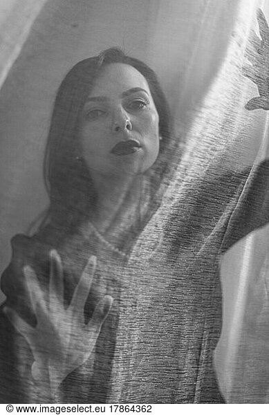 woman gazes through sheer translucent fabric black and white