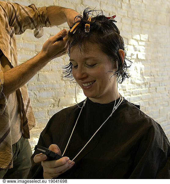 Woman getting a hair cut and listening to music.