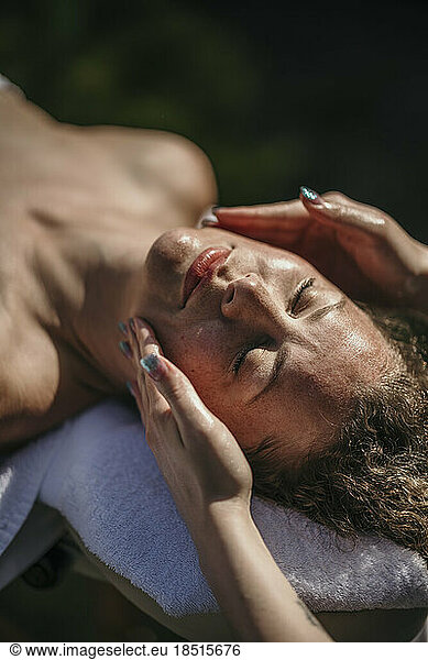 Woman getting facial massage at health spa