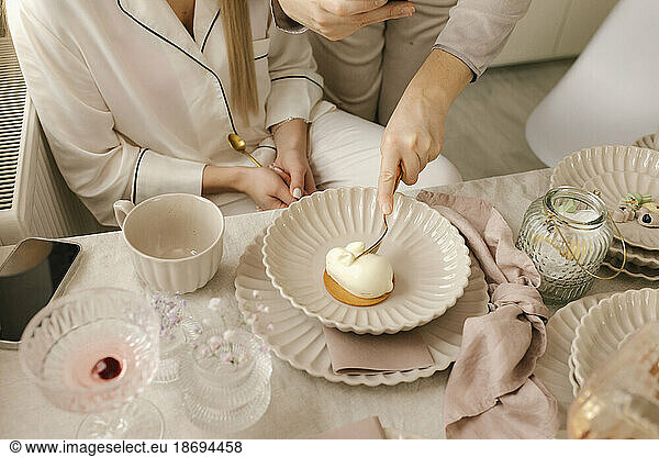 Woman having cake on plate by friend at dining table at home