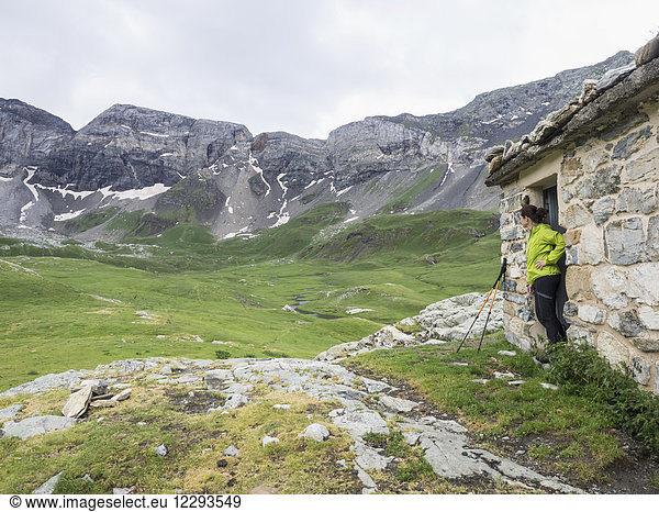 Woman hiker admiring scenic view of Cirque de Troumouse from mountain hut  France