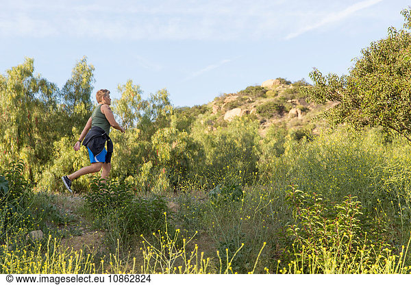 Woman hiker walking on wildflower covered outcrop