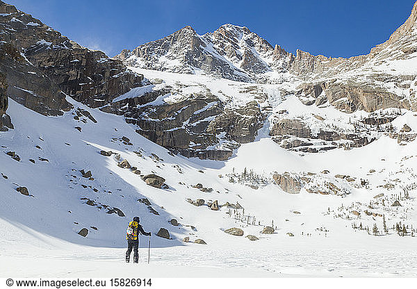 Woman hikes across frozen Black Lake  Rocky Mountain National Park