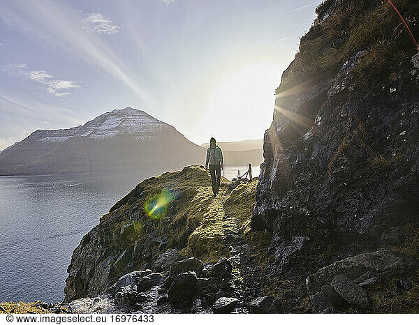 Woman hiking along oceanside trail in the Faroe Islands