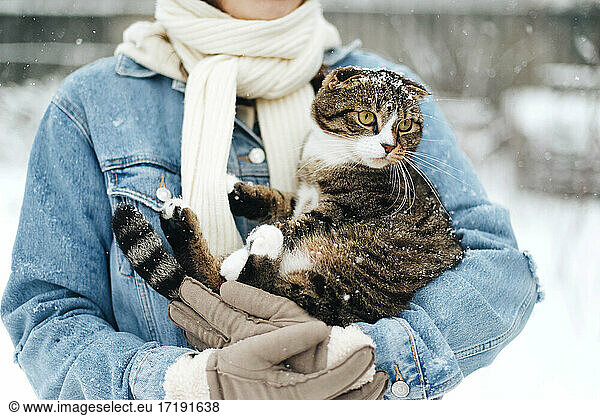 Woman holding a cat in snow