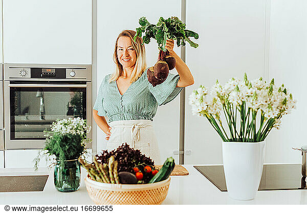 Woman holding beetroots while standing at the kitchen counter
