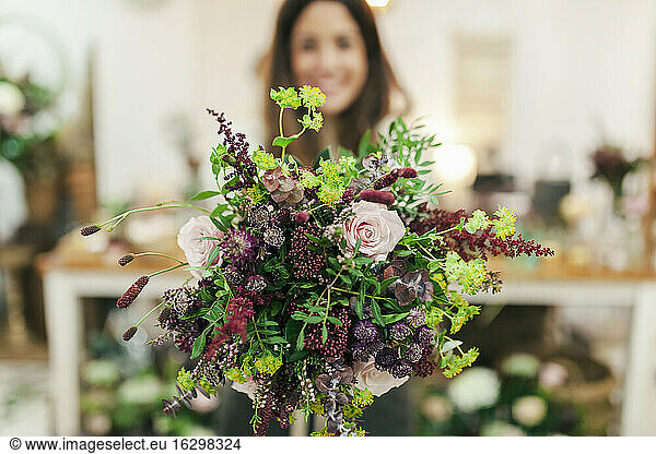 Woman holding bunch of flowers while standing at flower shop