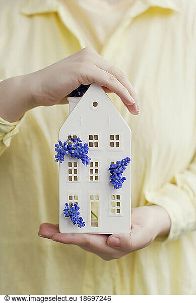 Woman holding ceramic house with blue grape hyacinth