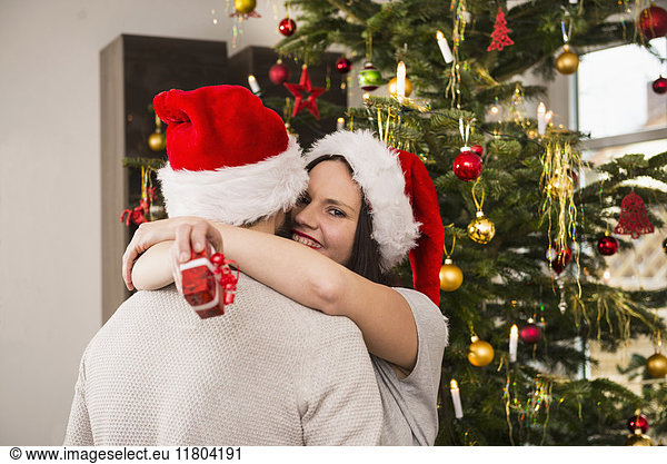 Woman holding Christmas gift hugging her husband
