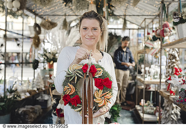 Woman holding Christmas wreath inside shop