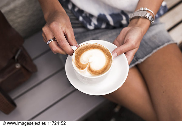 Woman holding coffee cup with cappuccino