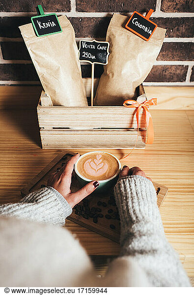 Woman holding coffee cup with latte art at cafe