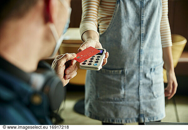 Woman holding contactless payment terminal for a customer paying by card