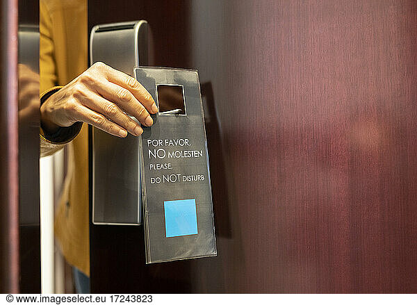 Woman holding do not disturb sign label at hotel door