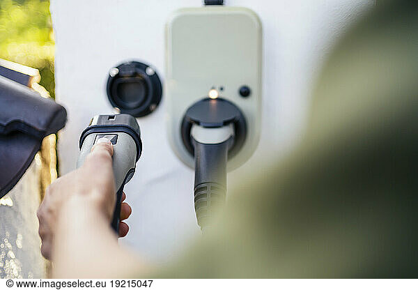 Woman holding electric plug at charging station