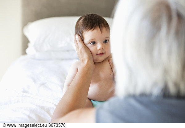 Woman holding granddaughter on bed