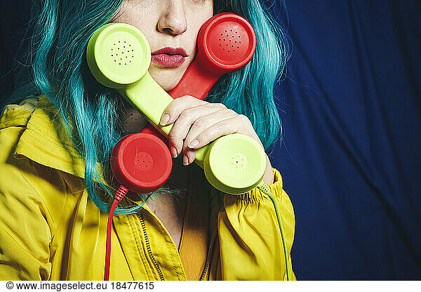 Woman holding green and red telephone receivers in cross shape