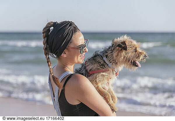 Woman holding her dog on beach