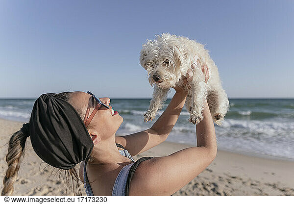Woman holding her dog on beach