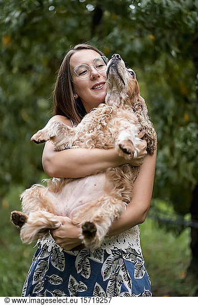 Woman holding her dog outdoors