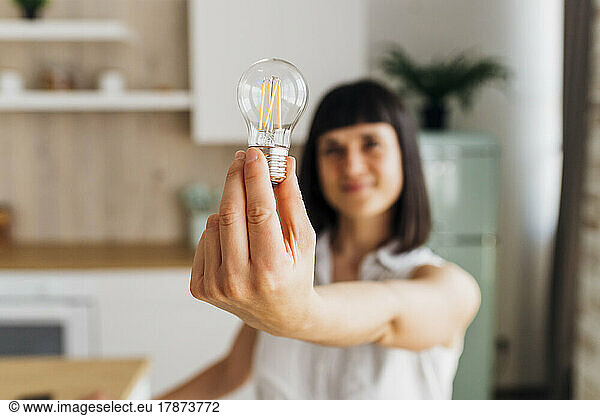 Woman holding light bulb at home