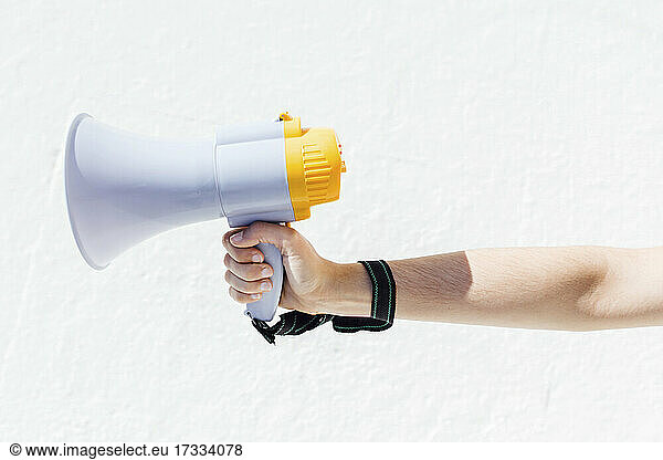 Woman holding megaphone by white wall
