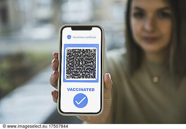 Woman holding mobile phone with QR code and check mark symbol on screen