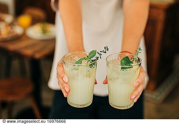 Woman holding non-alcoholic beverage  cold lemonade with mint and ice