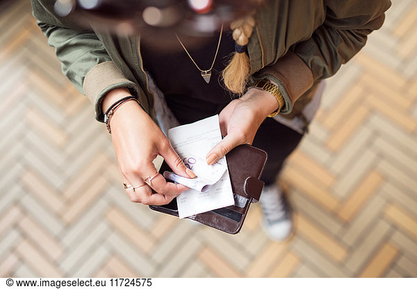 Woman holding open wallet with banknotes and receipts