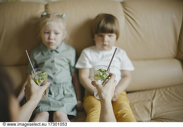 Woman holding out cocktails with reusable straws to children