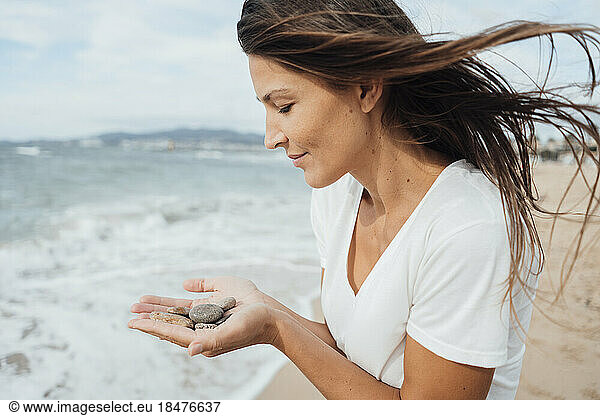 Woman holding pebbles at beach