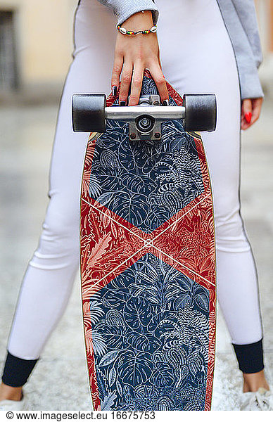 woman holding skateboard by hand