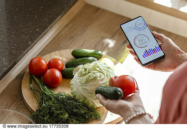 Woman holding smartphone with mobile app and vegetables