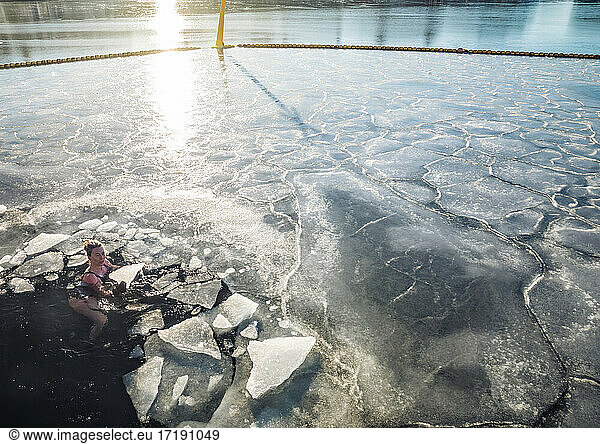 Woman Holding Solid Ice While Floating In Frozen Ocean in Denmark