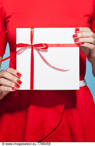 Woman holding white gift box with red bow  mid section