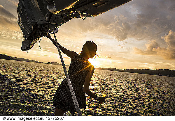 Woman holding wine glass standing on board a boat  sunset dinner cruise on Indian Ocean.
