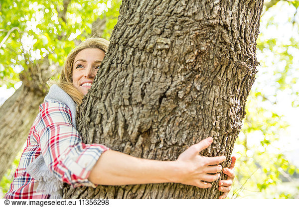 Woman hugging tree smiling