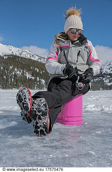 Woman ice fished on pink bucket in Colorado