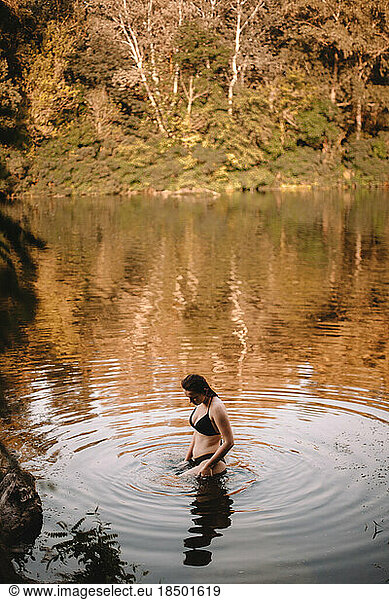 Woman in a bikini standing in river in forest