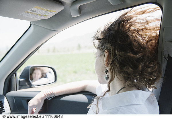 Woman in a car on a road trip  looking out of window.