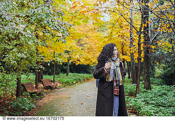 Woman in a coat and scarf walking in an autumn park