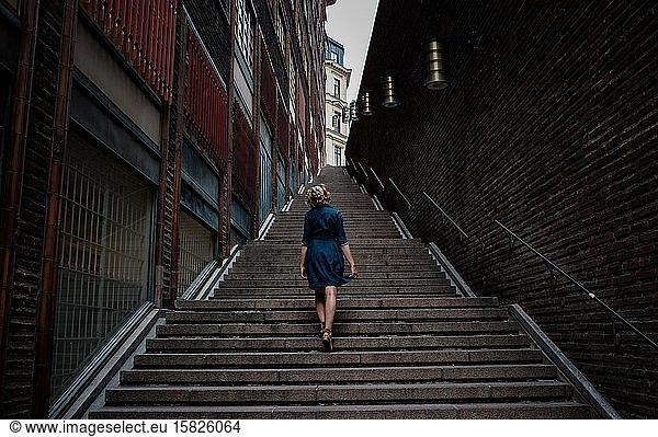 woman in a dress walking alone up many steps in the city centre
