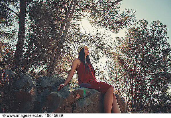 Woman in a forest sitting on rocks in a sunny spring day