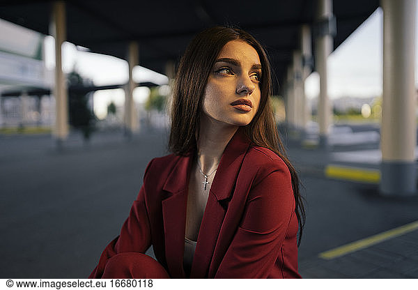 Woman in a red suit sitting at the bus station