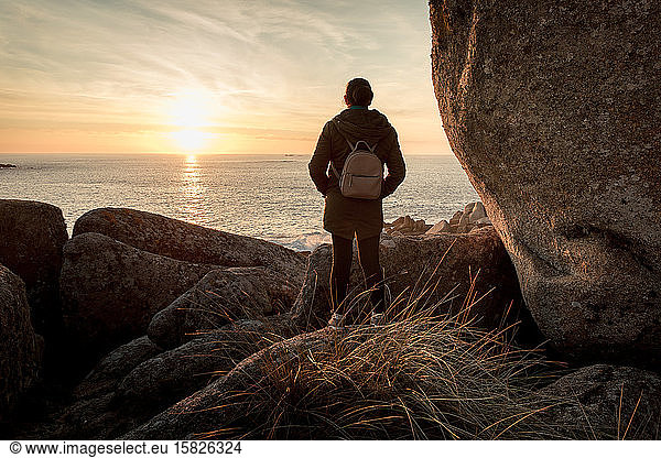 Woman  in a rocky place  watching the sunset in the coast