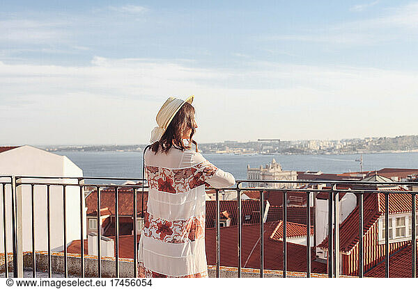 Woman in a straw hat from that back on a view point  roodftop view
