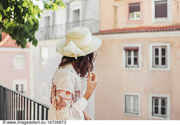 Woman in a straw hat from the back  curly hair  streets of Lisbon