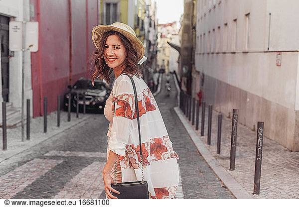Woman in a straw hat smiling and walking in an European town