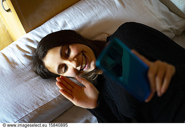 Woman in bed talking on video call.